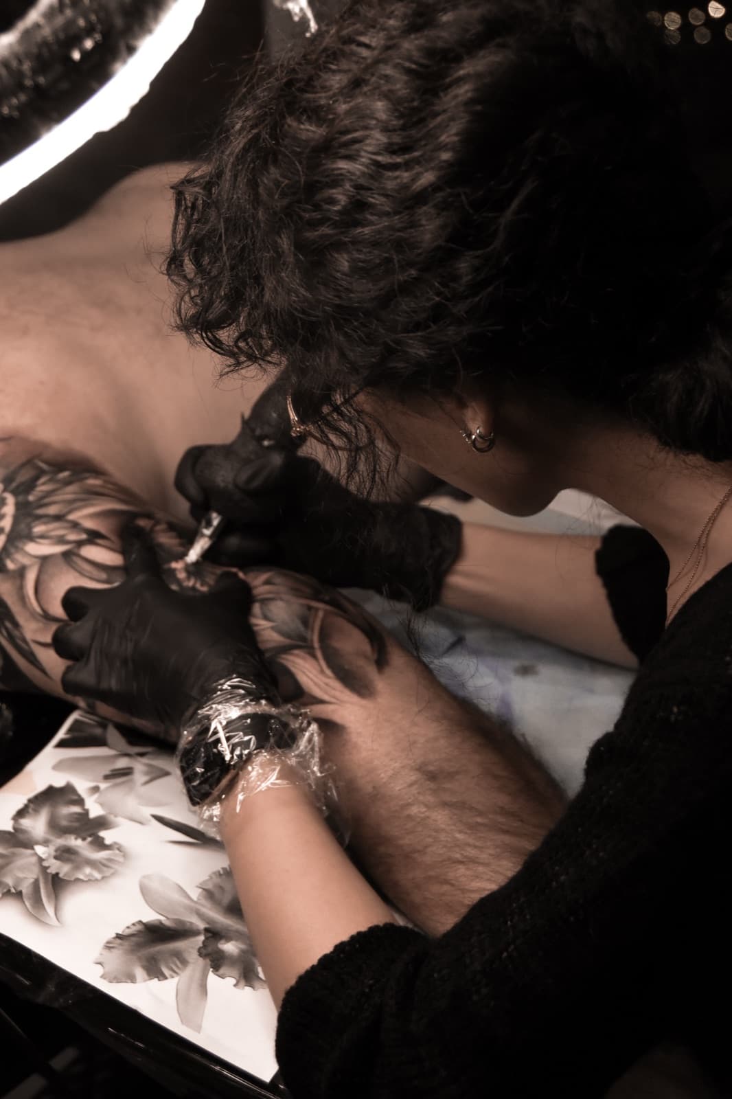 Juli Liverinova tattooing a fine-line botanical piece in her Vancouver studio